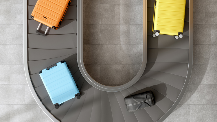 Overhead view of colourful suitcases on a conveyor belt at an airport.