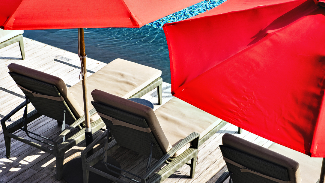 Red parasols next to a swimming pool.