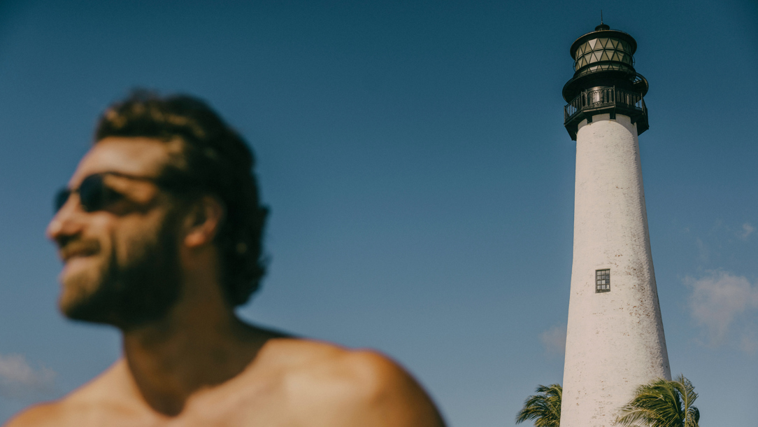 A man next to Florida Lighthouse on a windy day.
