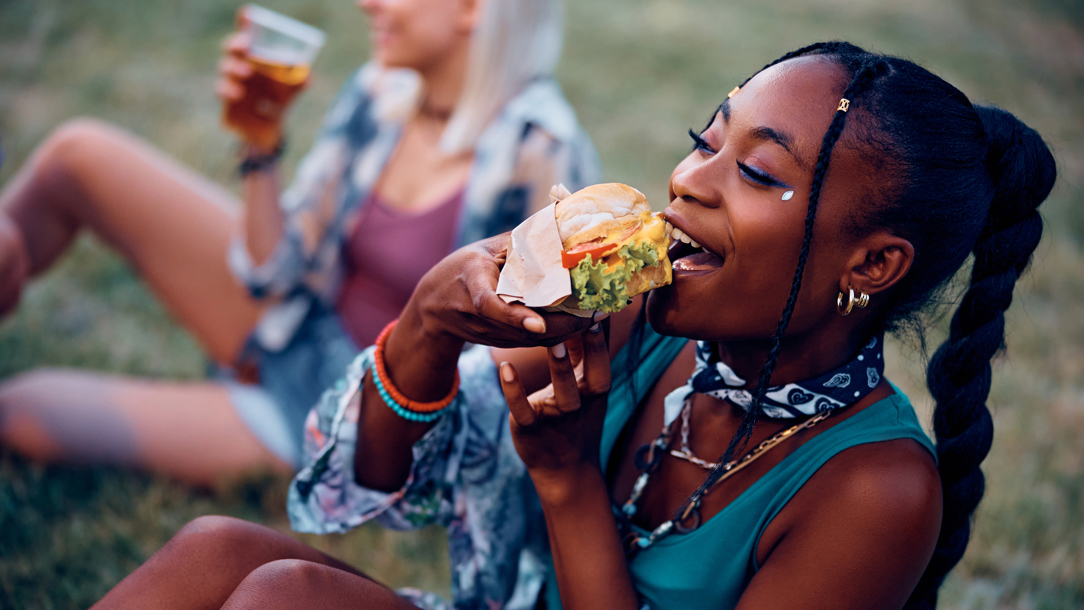 A young woman eating food at a summer festival.