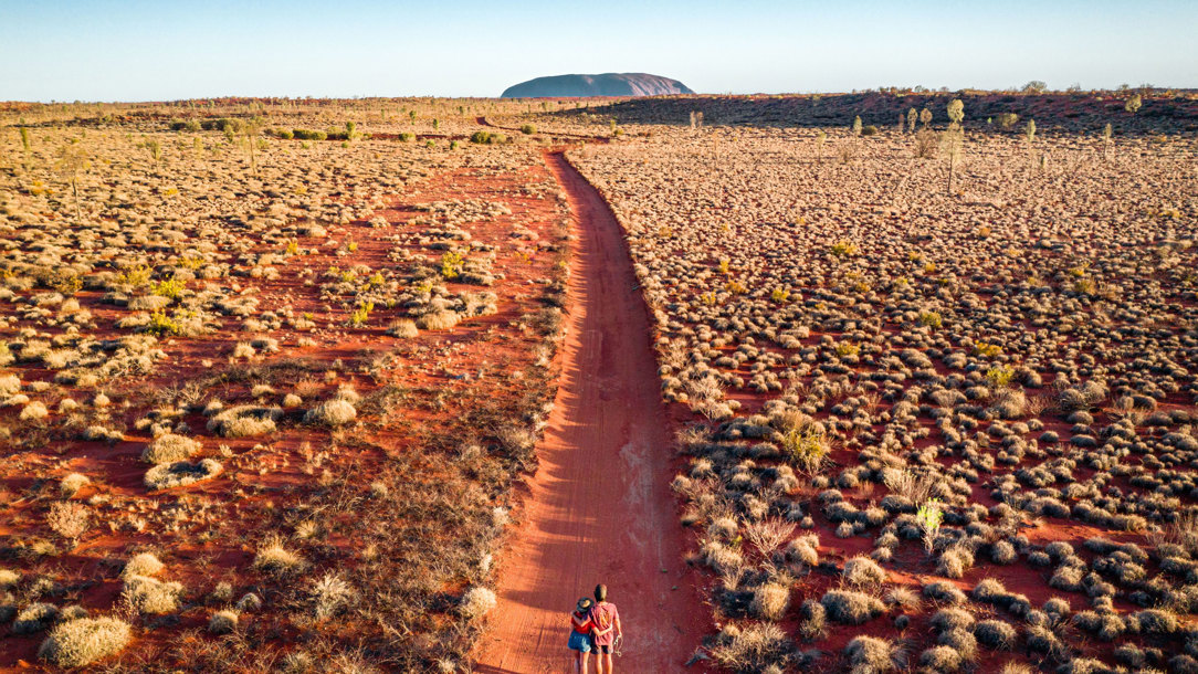 Two people walking towards Uluru in Australia.