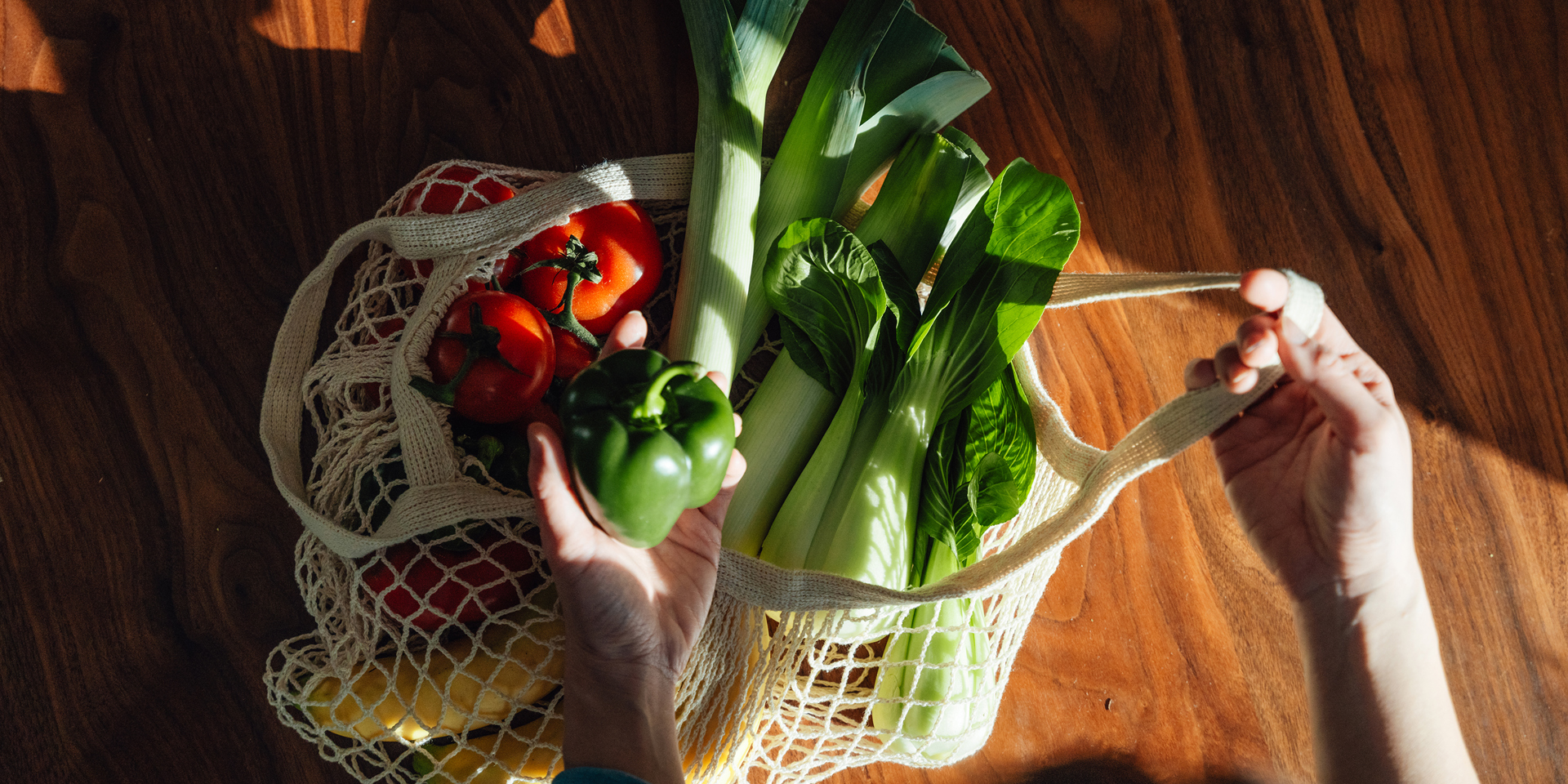 A string shopping bag with vegetables photographed from above.