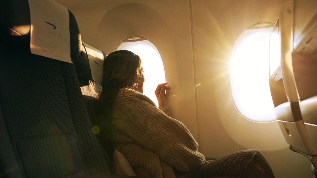 A lady looking out of the window on a British Airways flight.